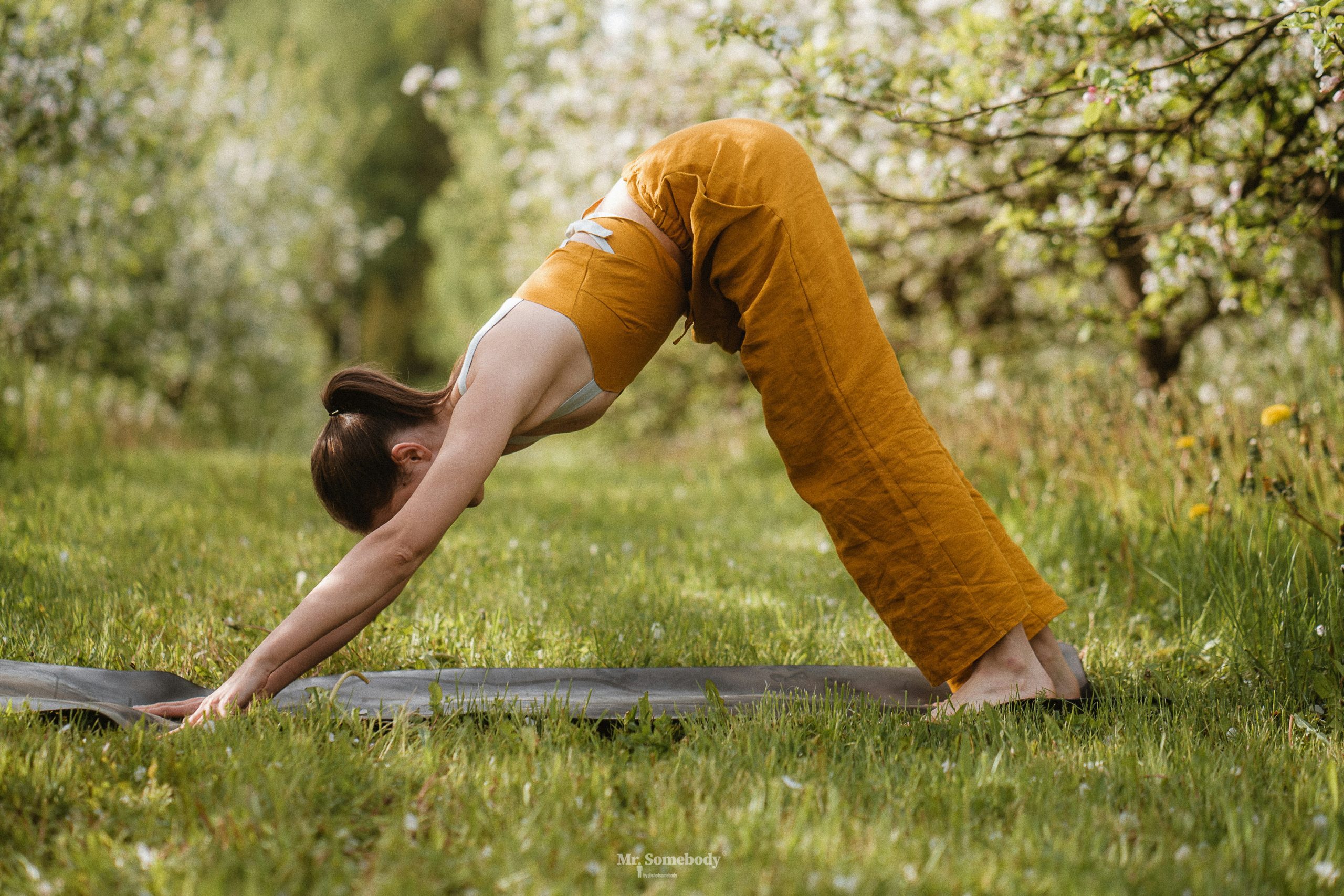 A woman wearing yellow doing yoga in the garden